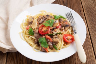 Mantar, domates ve beyaz bir plaka üzerinde krema sos spagetti