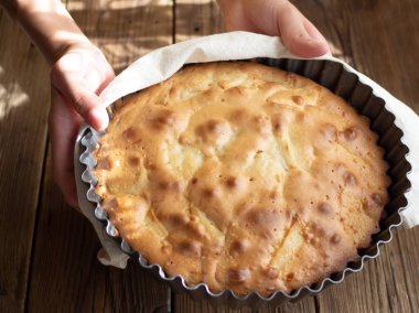 Ellerini bir taze pişmiş pasta ahşap arka plan üzerinde tutun. Menü giriş kitap tasarımı için iyi.