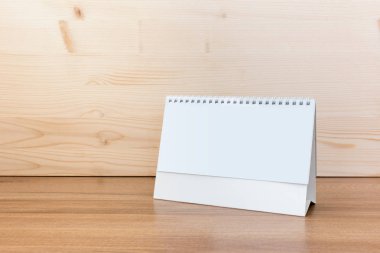 Ahşap zemin üzerinde beyaz boş kağıt masa spiral takvimi.