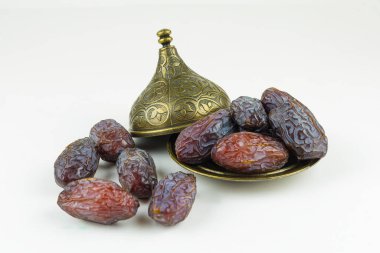 Beyaz arka planda bronz kaselerde tarihler. Türkçe Adı: HURMA.