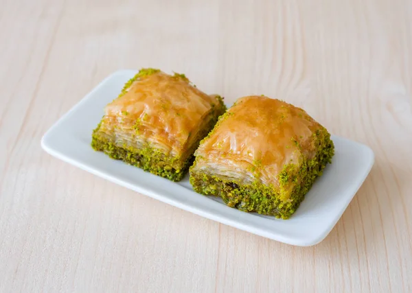 Turkish sweet baklava with plate on wooden background.