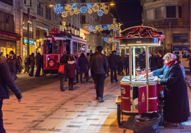 ISTANBUL, TURKEY - 1 Ocak 2018: Kestane satıcısı ve Istiklal Caddesi 'ndeki nostaljik kırmızı tramvay. Beyoğlu, Taksim, İstanbul. Türkiye.