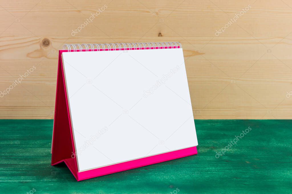 White blank paper desk spiral calendar on green wooden background