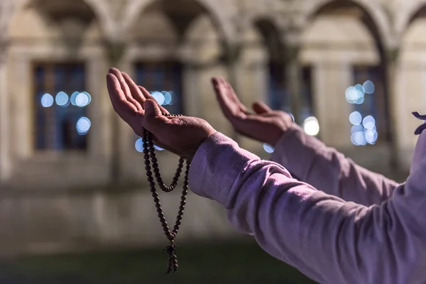 Praying Muslim Man with prayer-beads (Tesbih). Praying Muslim Man with mosque background in Ramadan Kareem. Istanbul, Turkey.