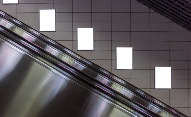 Metro istasyonunda boş bir poster modeli. Metro yürüyen merdiven arkaplanlı dört büyük dikey, portre oryantasyonu boş poster.