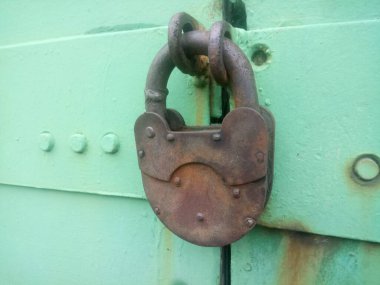 Yeşil metal kapıdaki paslı asma kilit.