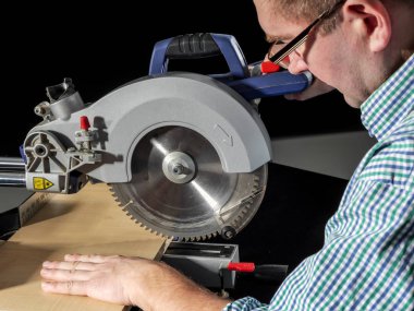 Marangoz, sürgülü Mitre testeresi kullanarak keten kesiyor.