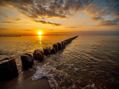 Gün batımına karşı eski ahşap dalga kırıcılar