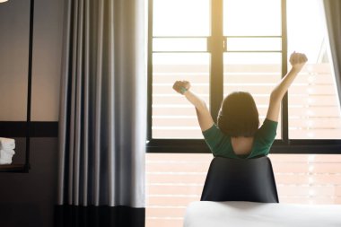 Kadın rahatlatıcı ve elleri ile sandalyede oturan arka görünümü yukarı ve sabah evde pencereye bakarak