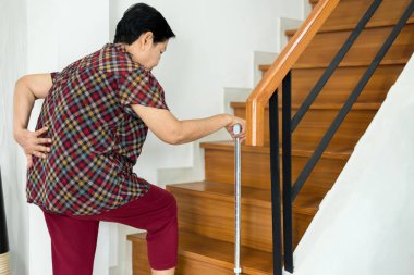Asyalı yaşlı yaşlı kadın evde merdiven üzerinde yürürken bel bel ağrısı muzdarip