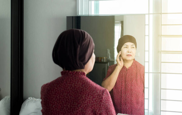 Chemotherapy concept,Senior asian woman with disease cancer standing and looking something in her bedroom,Elderly female feeling depressed and upset