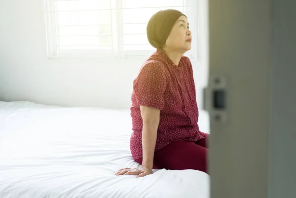 Senior asian woman with disease cancer sitting in her bedroom,Elderly female feeling depressed and upset,Chemotherapy concept