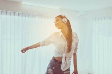 Güzel genç kadın kulaklık kullanarak müzik ve yatak odasında dans dinleme, Rahatlatıcı zaman