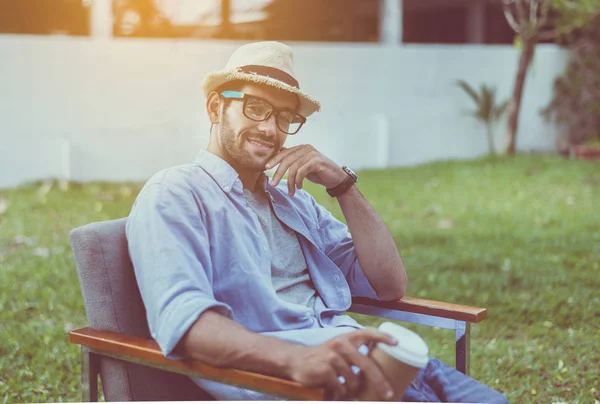 Caucasian man wearing hat and glasses sitting on chair at outdoor,Happy and smiling,Relaxing time
