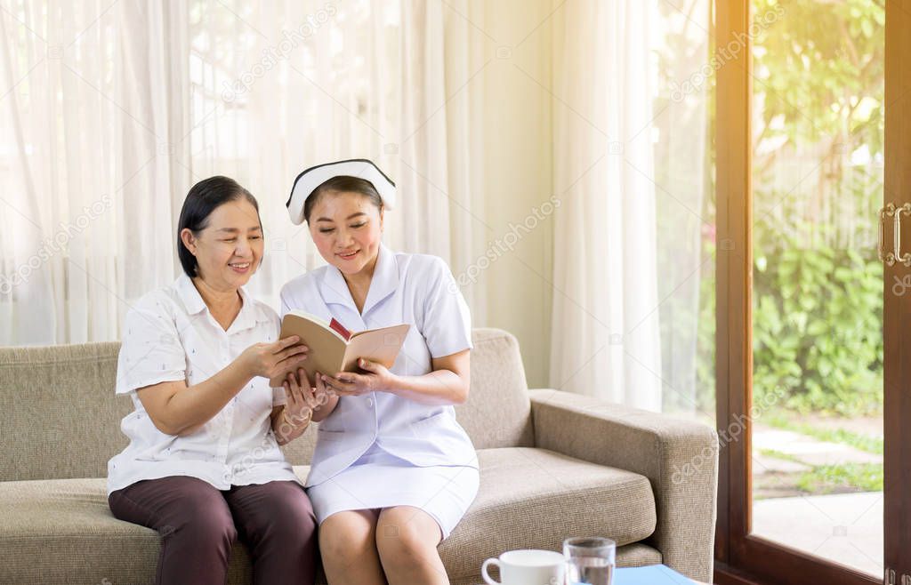 Nurse taking care reading a book to her patient mature asian elderly woman,Senior healthy concept