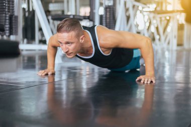 Aktif güçlü adam şınav çekiyor ve spor salonunda yerde egzersiz yapıyor.