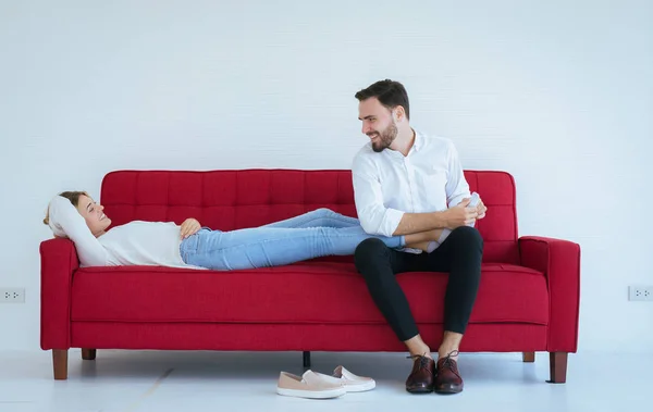 Young man hands giving massage to woman foots on red sofa,foot soles massage