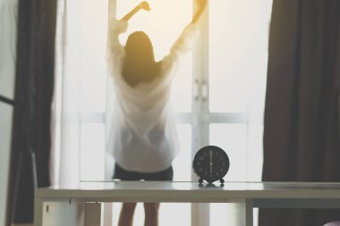 Beyaz gömlek streç tembel içinde ferahlatıcı kadın Bulanık sabah 6'da uyandıktan sonra, Alarm saat, Geri görünüm