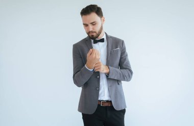 Resmi smokinli, takım elbiseli, beyaz arka planda duran, mesaj için alan kopyalayan ve kesilen yakışıklı beyaz erkek.