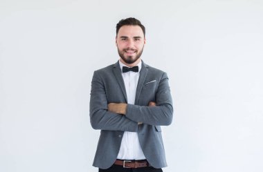 Resmi smokin sakallı yakışıklı beyaz adam ve beyaz arka plan üzerinde takım elbise ayakta ve çapraz kollar, Metin ve kesmek için boşluk kopyalayın