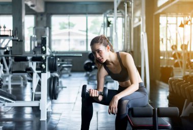 Dambıllı sportif kadın egzersizi,Spor giyimde kadın spor salonunda egzersiz yapıyor