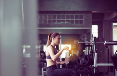 Spor salonunda oturan ve içme suyu çekici kadın, Asyalı kadın mola ve egzersiz sonrası relex