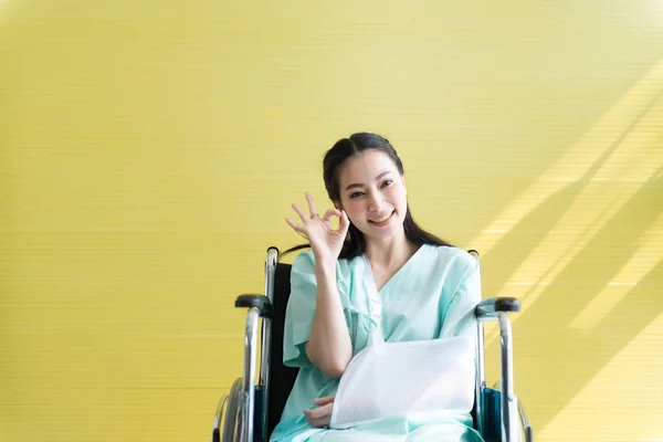 アジアの美しい女性患者があなたの手を上げるOkサインシンボルと病院で車椅子に座って 幸せと笑顔 — ストック写真