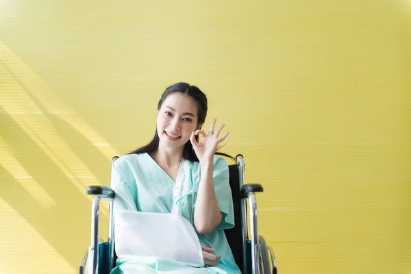 アジアの美しい女性患者があなたの手を上げるOkサインシンボルと病院で車椅子に座って 幸せと笑顔 — ストック写真