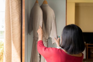 Gardırop ta raydan asılı elbiseler bornoz seçen kadın