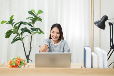 Asyalı güzel bir kadın arkadaşlarıyla video konferans görüşmesi yapıyor, evden çalışıyor, evde çalışıyor. 