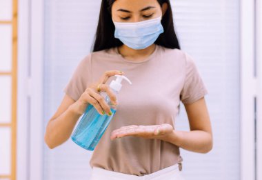 Evde hijyen koronavirüsü koruması için pompa şişesine dezenfektan jeli kullanan bir kadın.