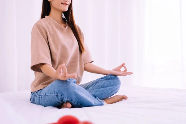 快乐的女人坐在床上练习瑜伽冥想 早上醒来后做运动 健康和生活方式的概念 — 图库照片