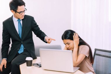Asyalı patron ofisteki stresli kadın çalışanı işaret ediyor.
