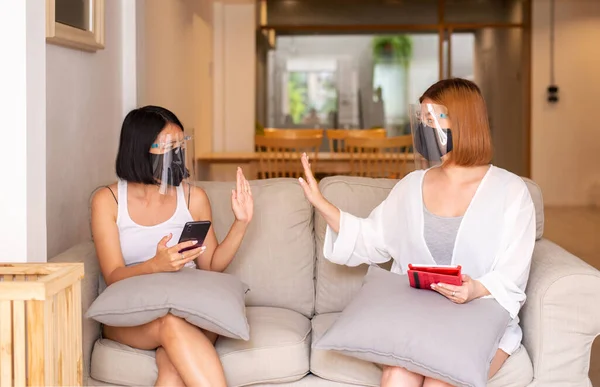 顔のシールドと保護マスクを身に着けているアジアの女性は 自宅で広がるコロナウイルス 社会的距離 新しい通常の間に接触を避けるために手の触れを示さない — ストック写真