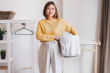 Mutlu Asyalı kadın evde sepetle çamaşır yıkıyor.