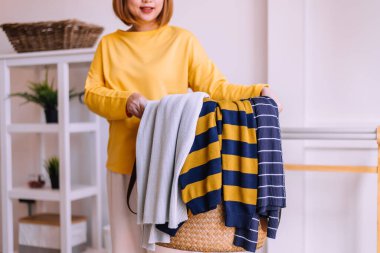 Genç Asyalı kadın evde sepetle çamaşır yıkıyor.