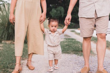 Mutlu Asyalı bebek anne ve babasıyla ilk adımları atmayı öğreniyor.