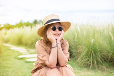 Doğada çimlerin üzerinde oturan mutlu Asyalı genç kadınlar, açık hava portresi