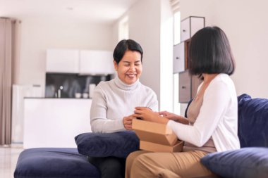 Kızının evde annesine hediye paketi vermesi, Anneler Günü konsepti.