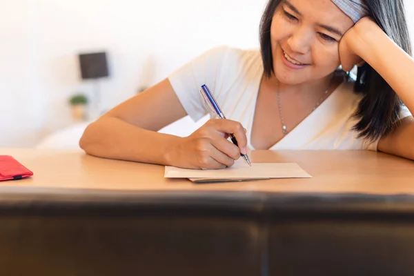 Happy asian woman writing greeting cards at home for next holiday