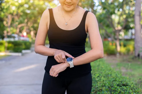 Fit women using smart watch for running and checking device at outdoor in the morning