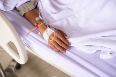 Hasta yatağında battaniyenin altında yatarken damardan serum fizyolojik verip ellerini kapat.