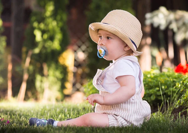 美しい春の日に庭で花を見て草の上に座っている赤ちゃん — ストック写真