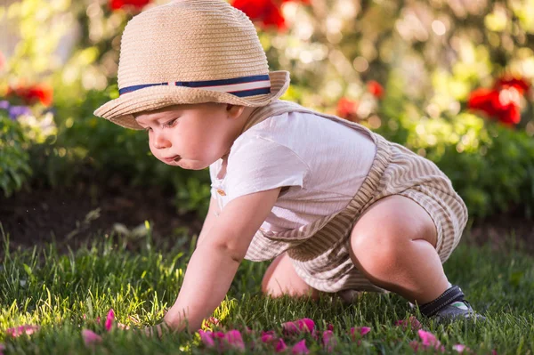 美しい春の日に庭で花を見て草の上に座っている赤ちゃん — ストック写真