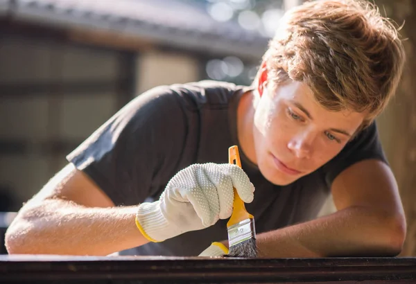Joven Hombre Guapo Está Pintando Cerca Madera Con Cepillo —  Fotos de Stock