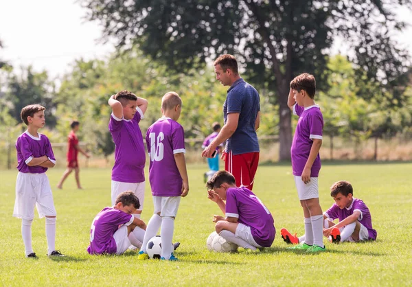 コーチはサッカーの試合で若いサッカー選手にアドバイスを与えています — ストック写真