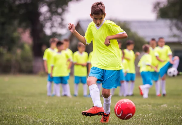 Boy kicking football on the sports field during soccer match