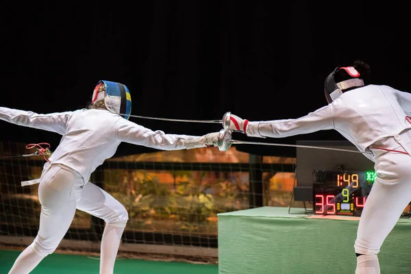 Two woman fencing athletes fight on professional sports arena