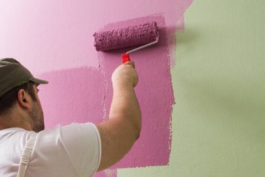 Genç adam boyama duvar boyama rulo olduğunu