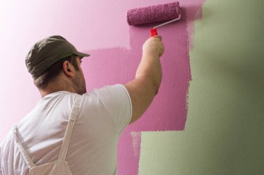 Genç adam boyama duvar boyama rulo olduğunu